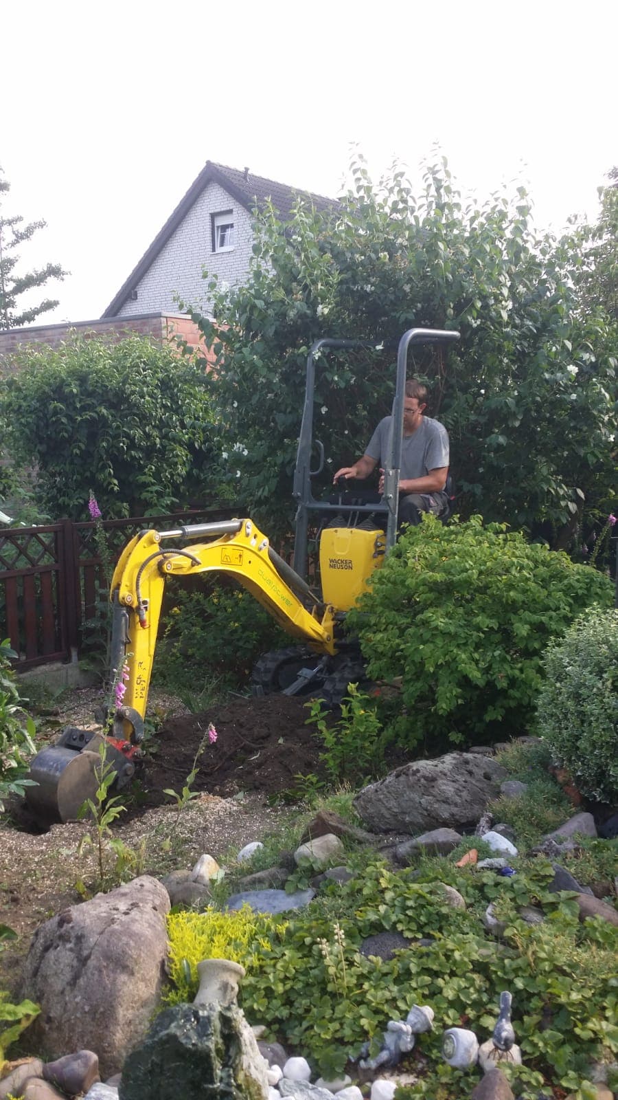 Minibagger bei Erdarbeiten in einem schmalen Garten